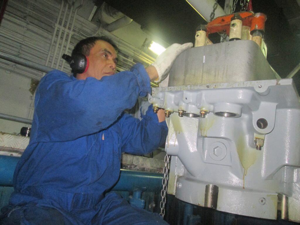 Lowering cylinder head into position on Bergen engine - Goltens